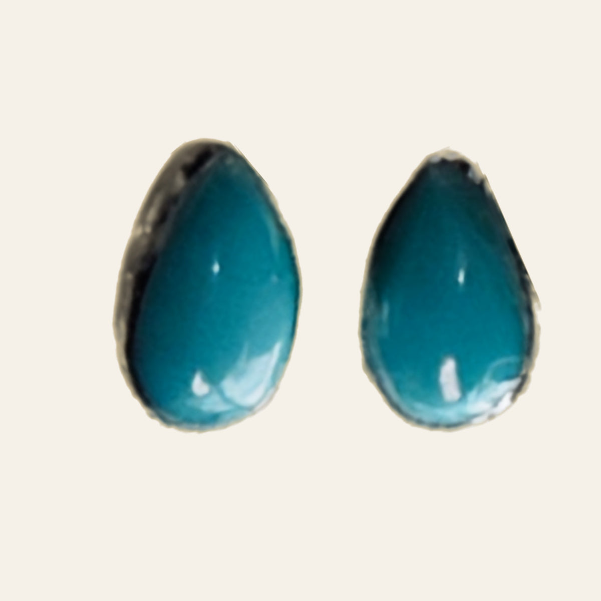 Natural Turquoise Teardrop Stud Earrings in Sterling Silver, shown on a cream background