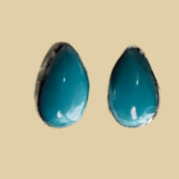 Natural Turquoise Teardrop Stud Earrings in Sterling Silver, shown on a desert plaster background