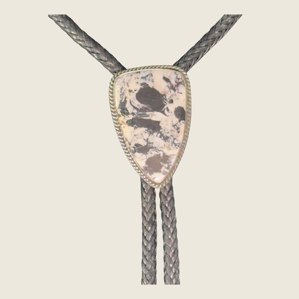 White buffalo bolo tie in Navajo sterling silver by P. Yazzie, shown on a bone linen background
