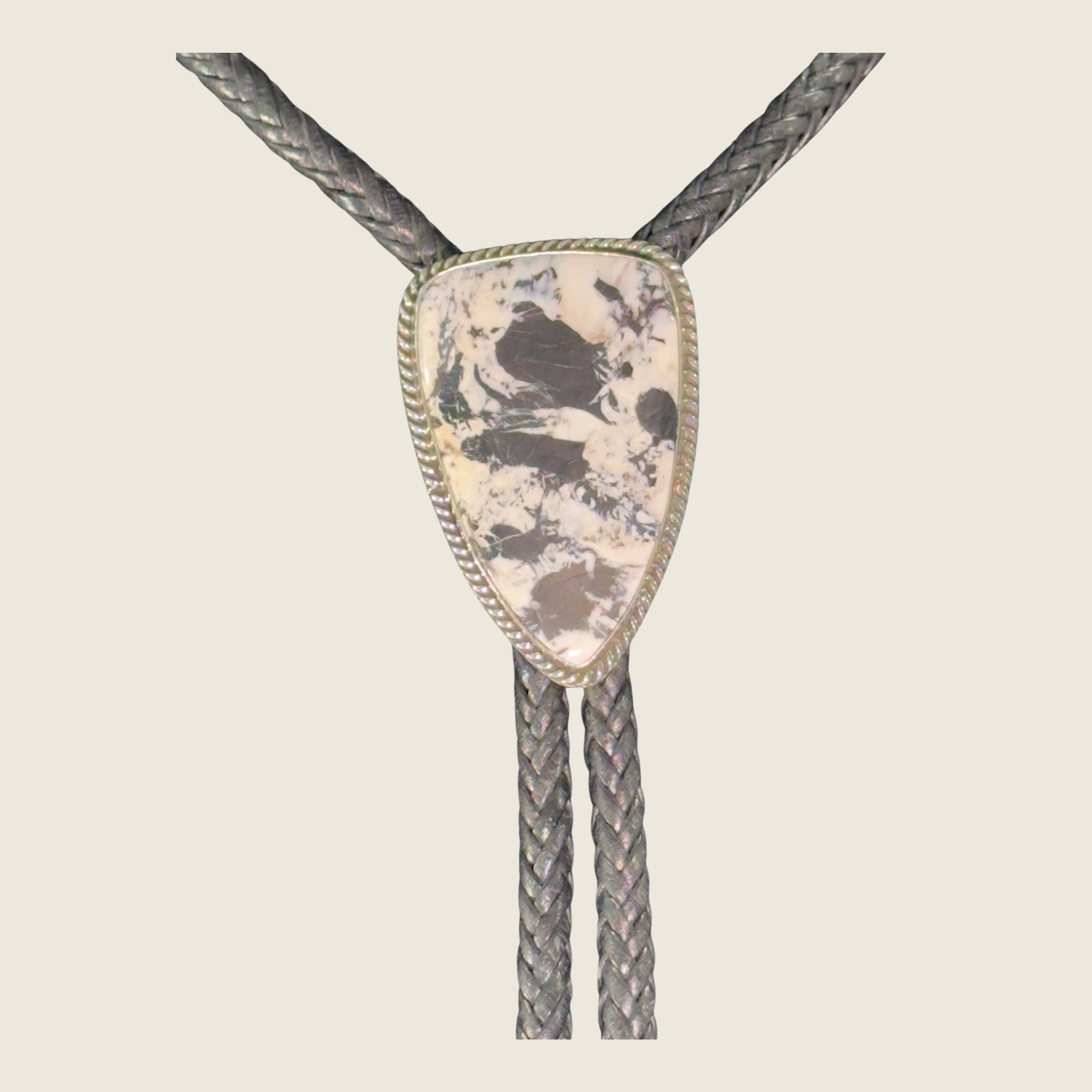White buffalo bolo tie in Navajo sterling silver by P. Yazzie, shown on a bone linen background