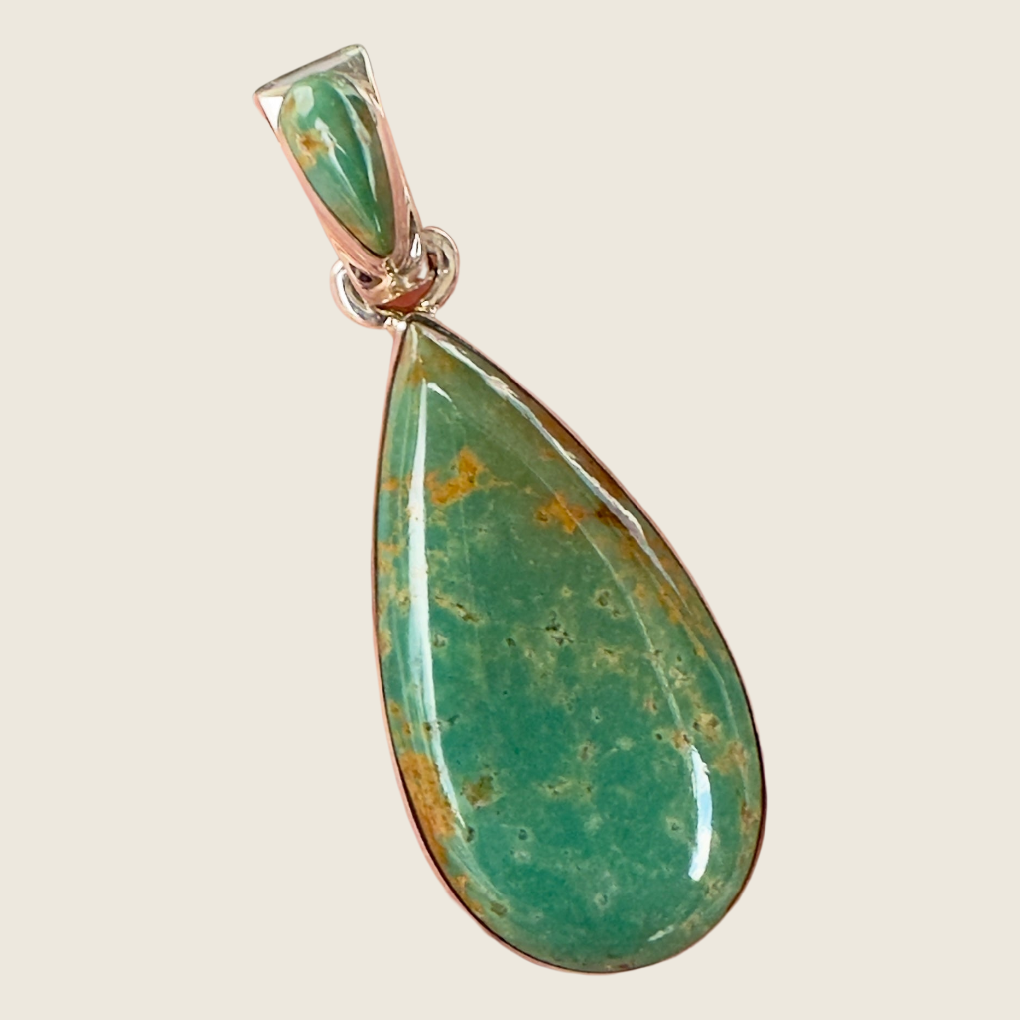 Royston turquoise teardrop pendant in sterling silver by Martinez, shown on a bone linen background