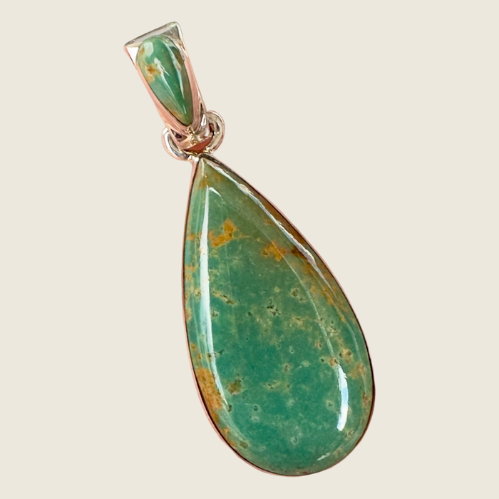 Royston turquoise teardrop pendant in sterling silver by Martinez, shown on a bone linen background