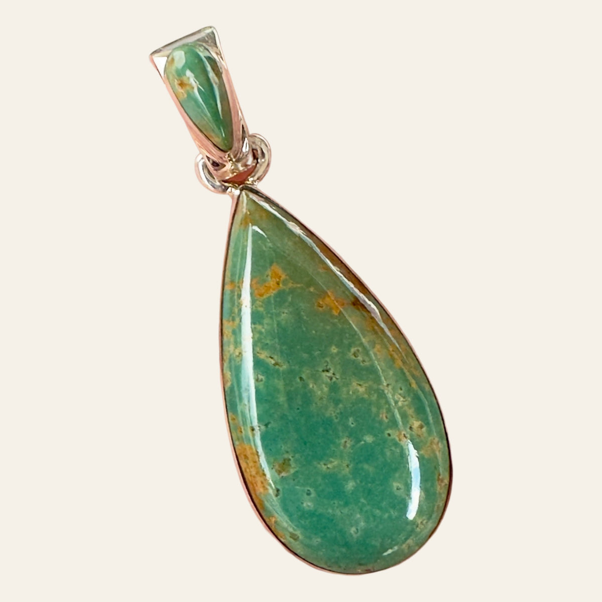 Royston Turquoise Teardrop Pendant in Sterling Silver, by Martinez, shown on a cream background