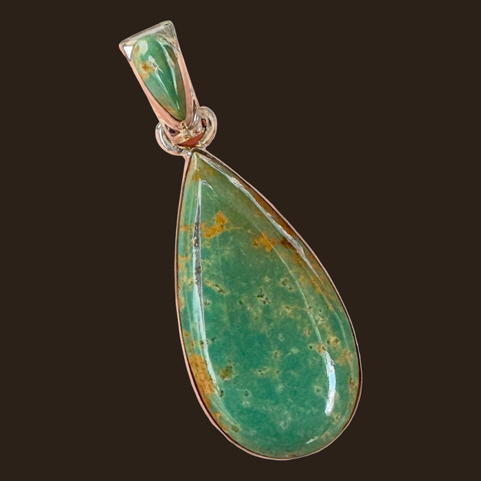 Royston Turquoise Teardrop Pendant in Sterling Silver, by Martinez, shown on an espresso background