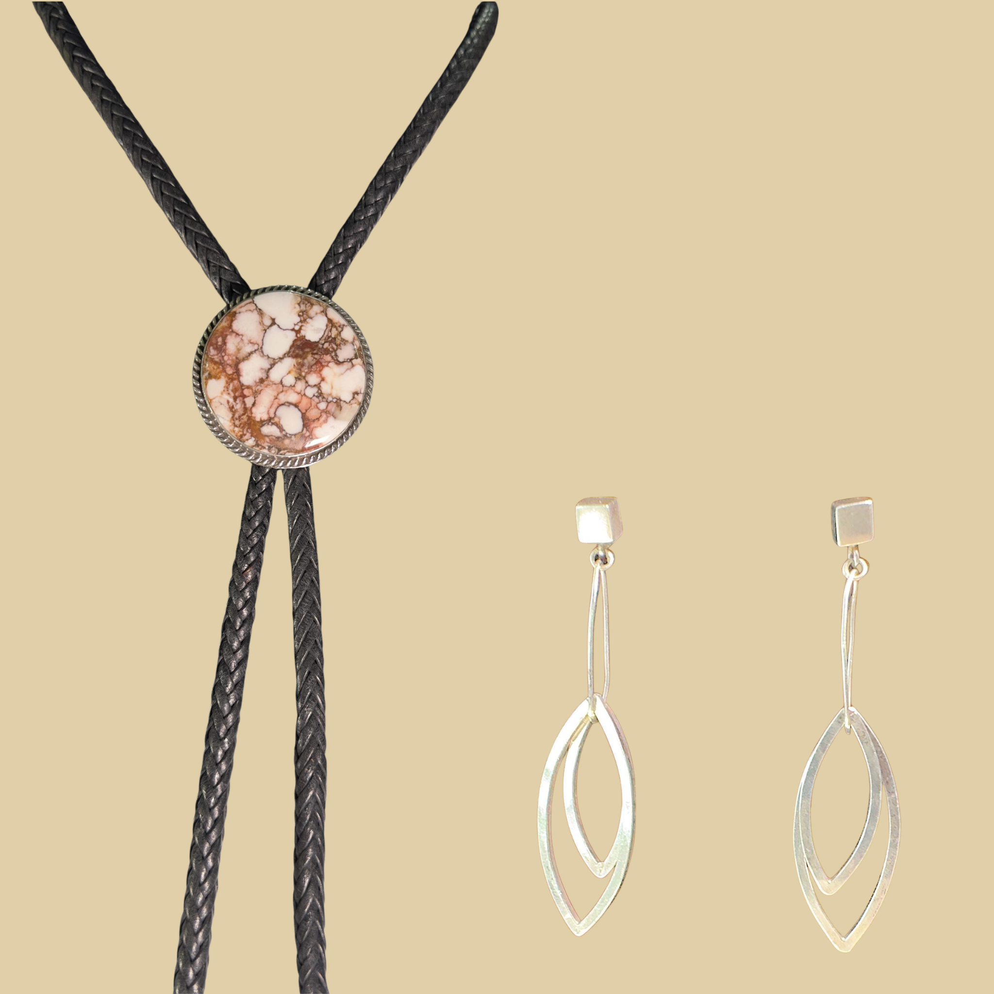 Wild horse bolo tie and leaf dangle earrings jewelry set in sterling silver, shown on a desert plaster background