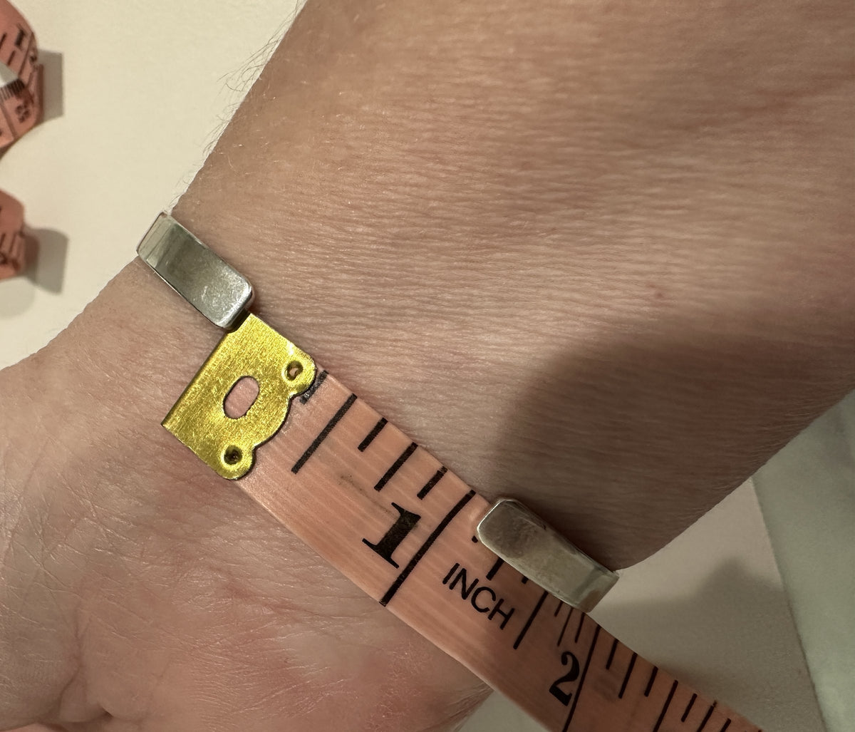 Tape measure showing the 1 inch opening between the plain sterling silver terminals at the back of the Don Lucas Sleeping Beauty turquoise row bangle, worn on a 6 1/2 inch wrist