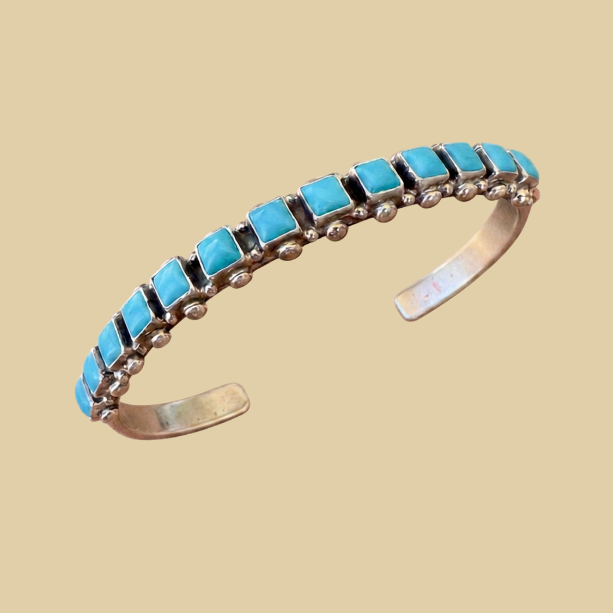 Sleeping Beauty Turquoise Row Bangle in Sterling Silver, by Don Lucas, shown on a desert plaster background