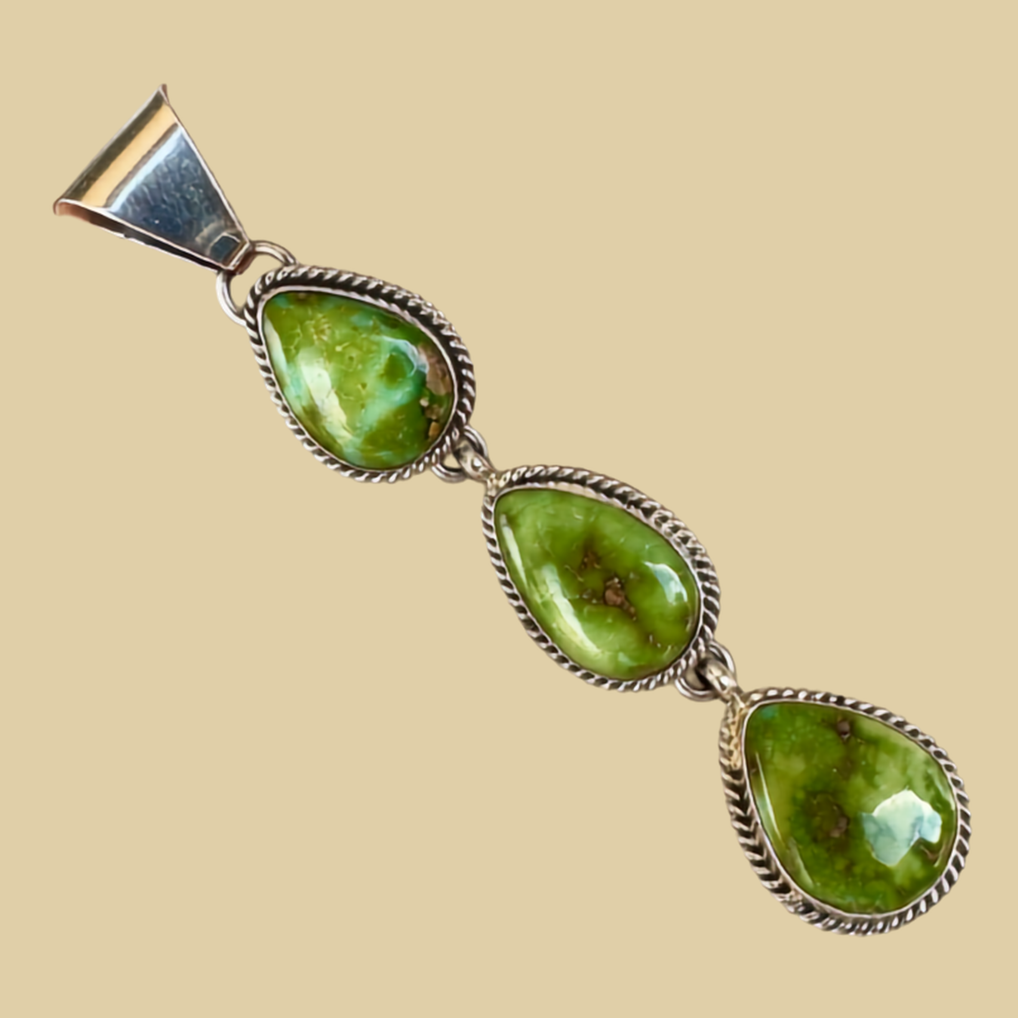 Sonoran Mountain Turquoise Triple Teardrop Pendant in Sterling Silver, by C. Wylle, shown on a desert plaster background