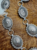 Stamped silver concho belt with sixteen oval conchos joined by round chain links