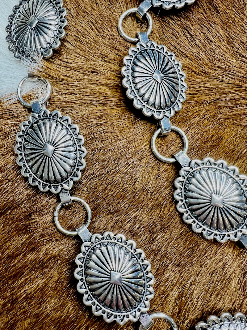 Stamped silver concho belt with sixteen oval conchos joined by round chain links