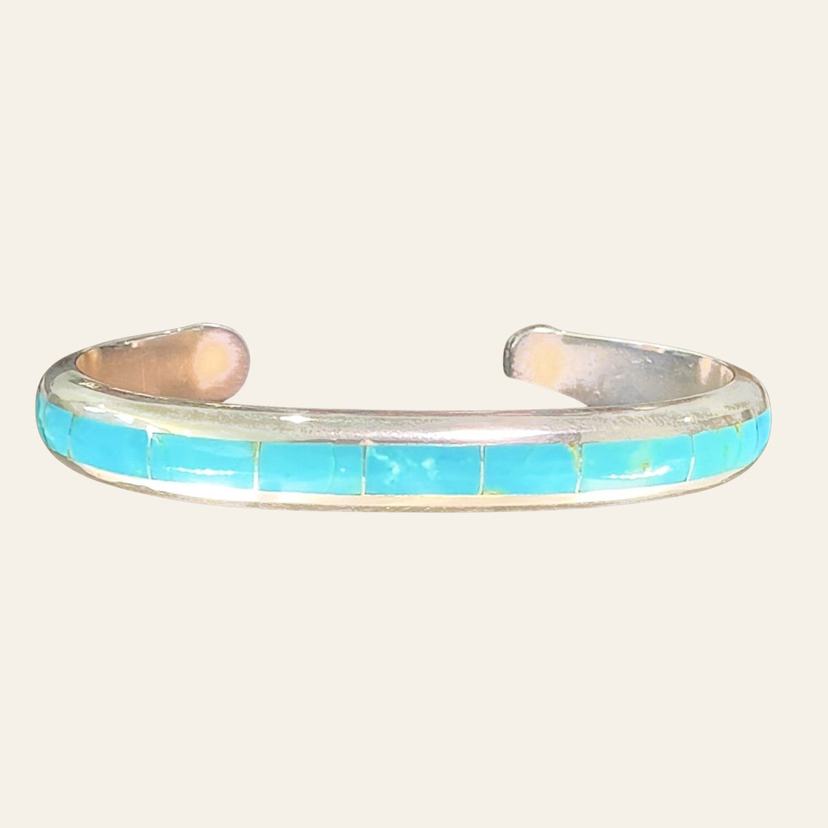 Turquoise Channel Inlay Cuff Bracelet in Zuni Sterling Silver, by Johnny Coonsis, shown on a cream background