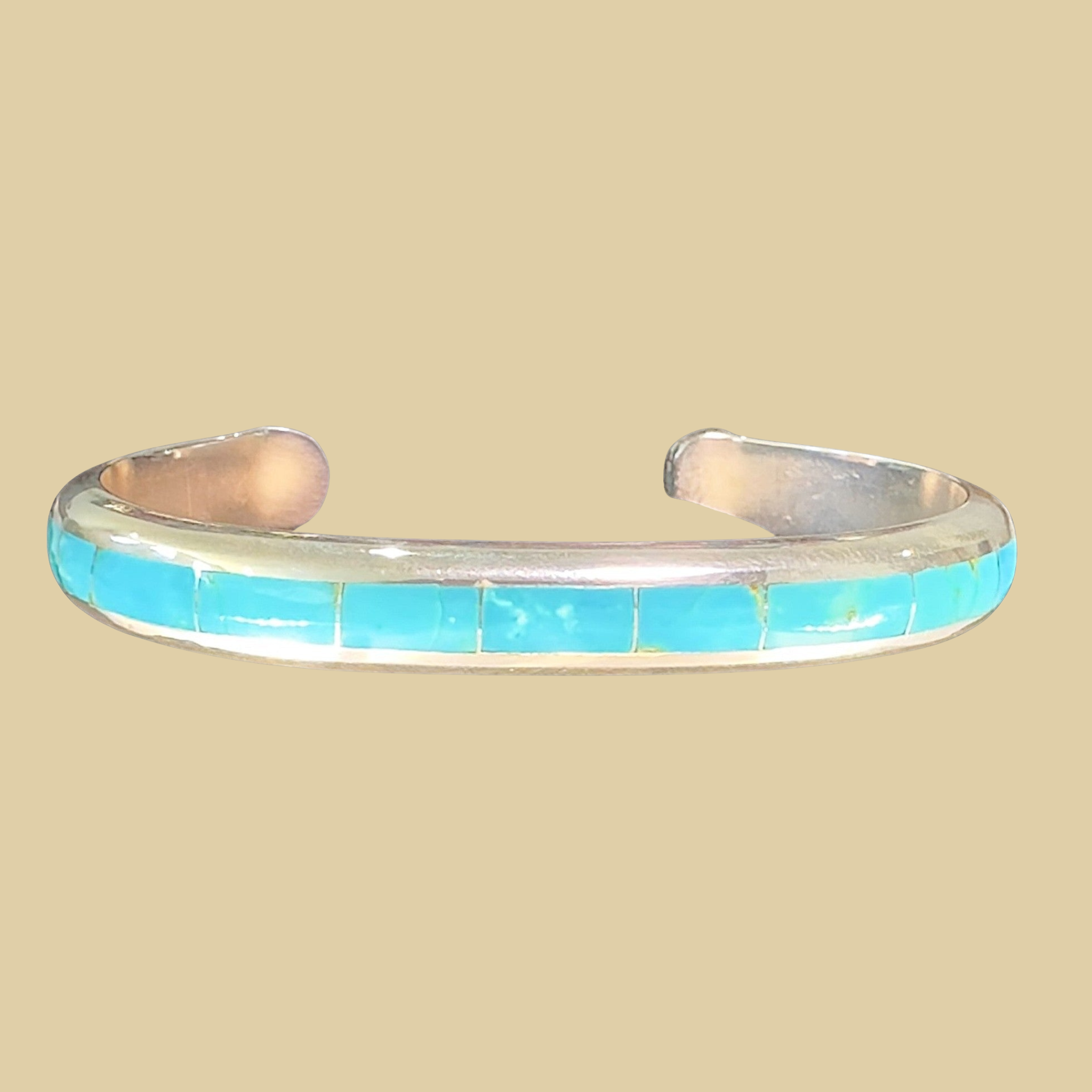 Turquoise Channel Inlay Cuff Bracelet in Zuni Sterling Silver, by Johnny Coonsis, shown on a desert plaster background