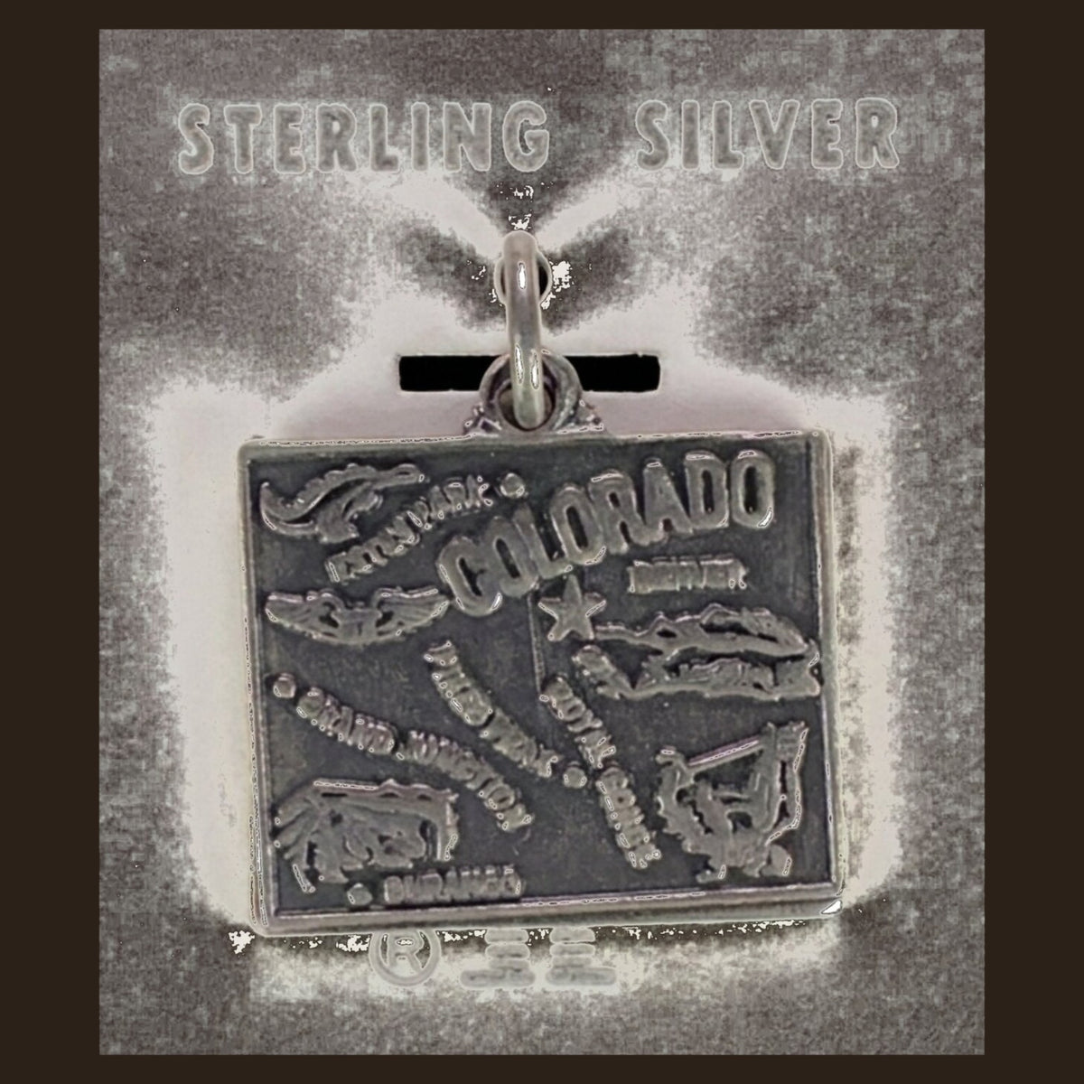 Vintage Maisel's Sterling Silver Colorado Map Charm, New Old Stock, shown on an espresso background