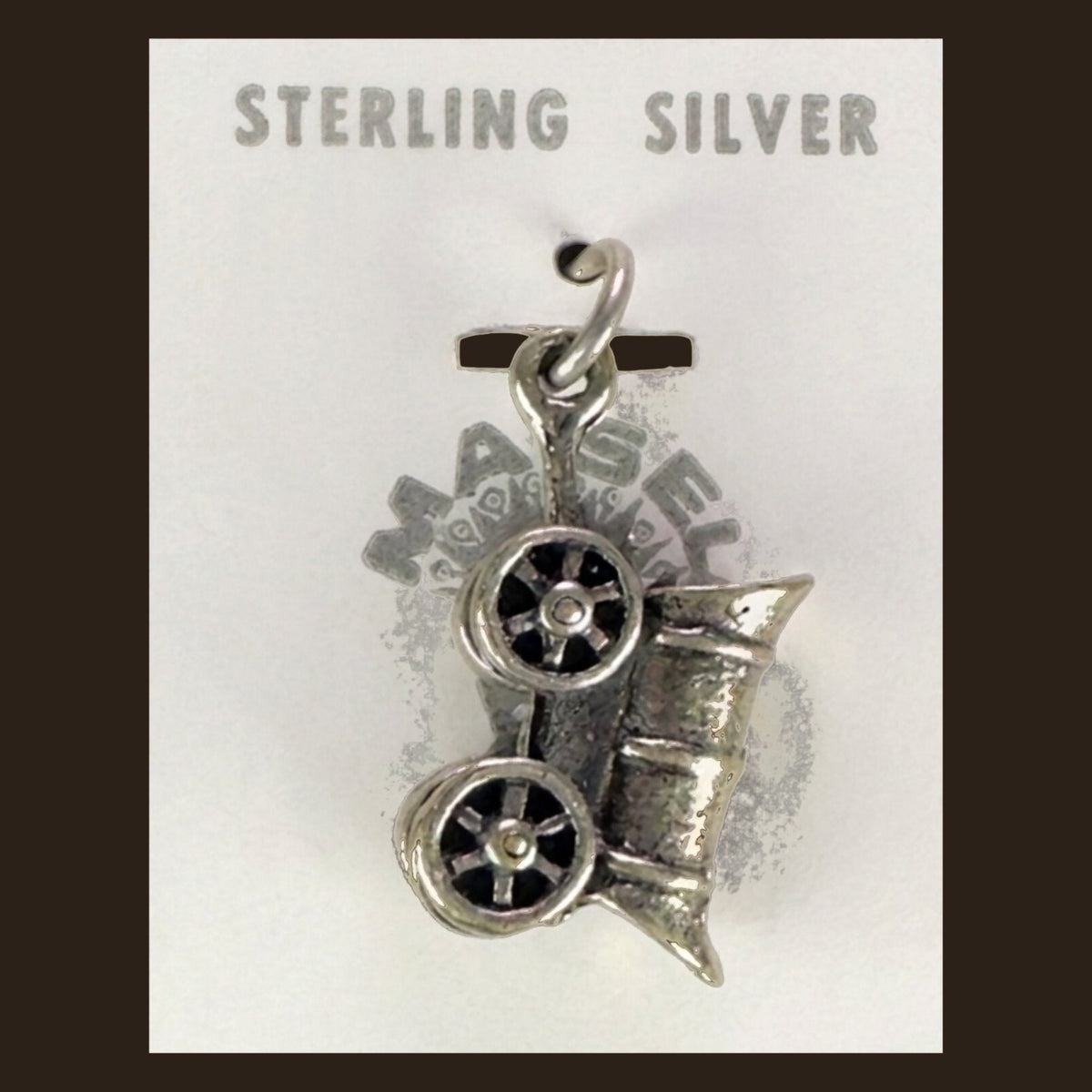 Vintage Maisel's Sterling Silver Covered Wagon Charm, New Old Stock, shown on an espresso background