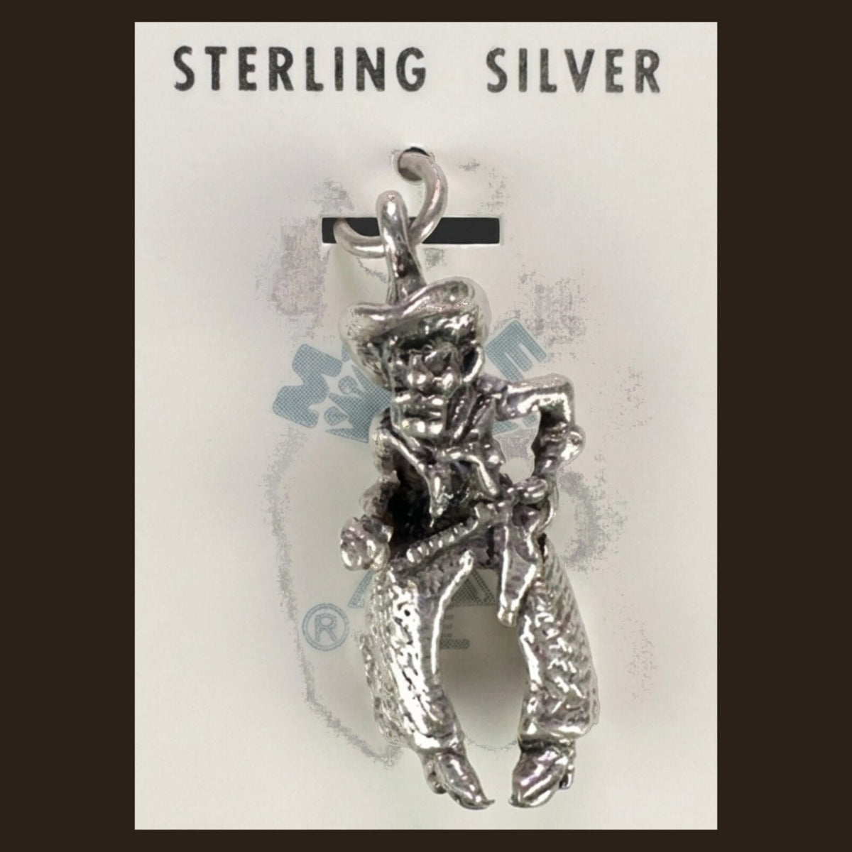 Vintage Maisel's Sterling Silver Cowboy Charm, New Old Stock, shown on an espresso background