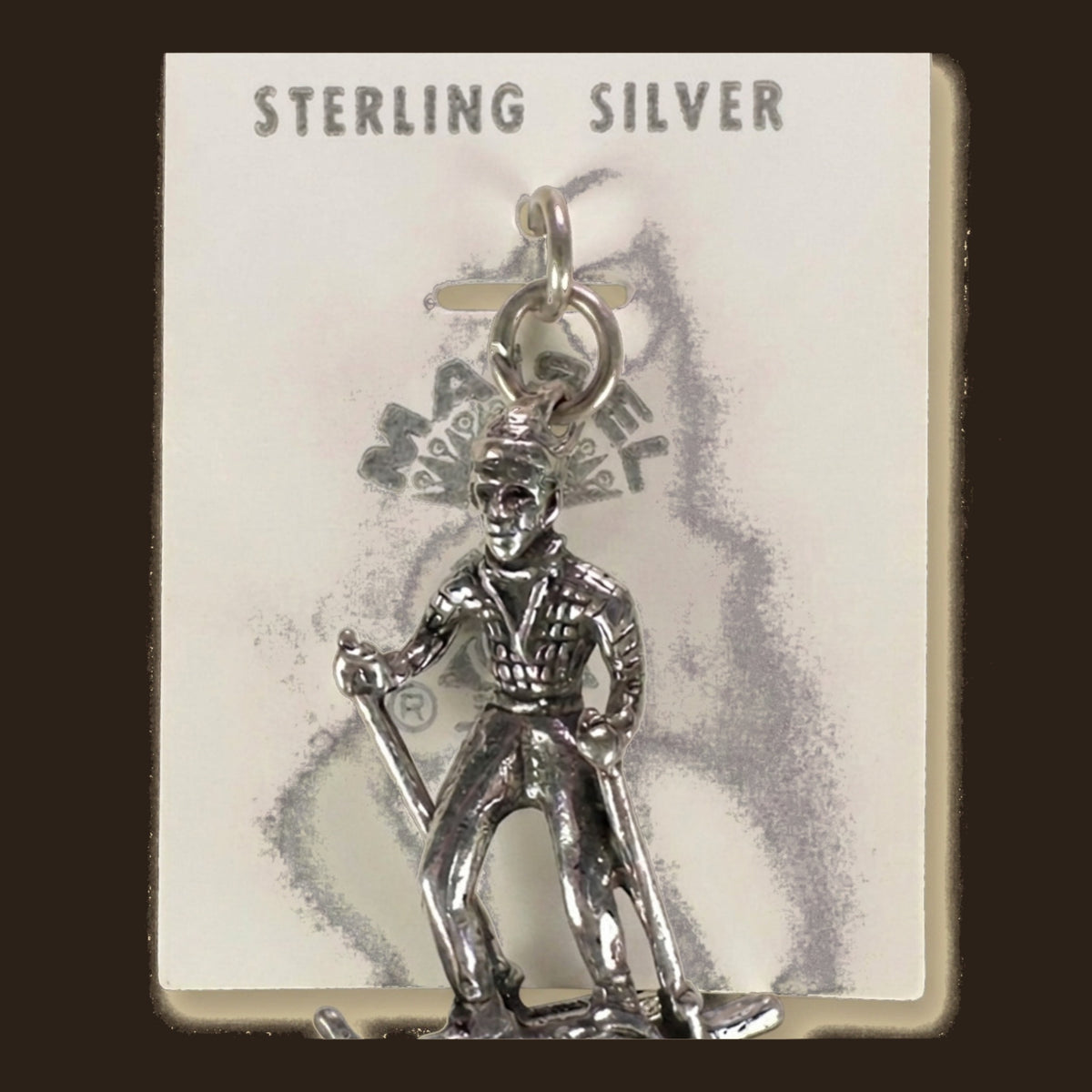 Vintage Maisel's Sterling Silver Skier Charm, New Old Stock, shown on an espresso background