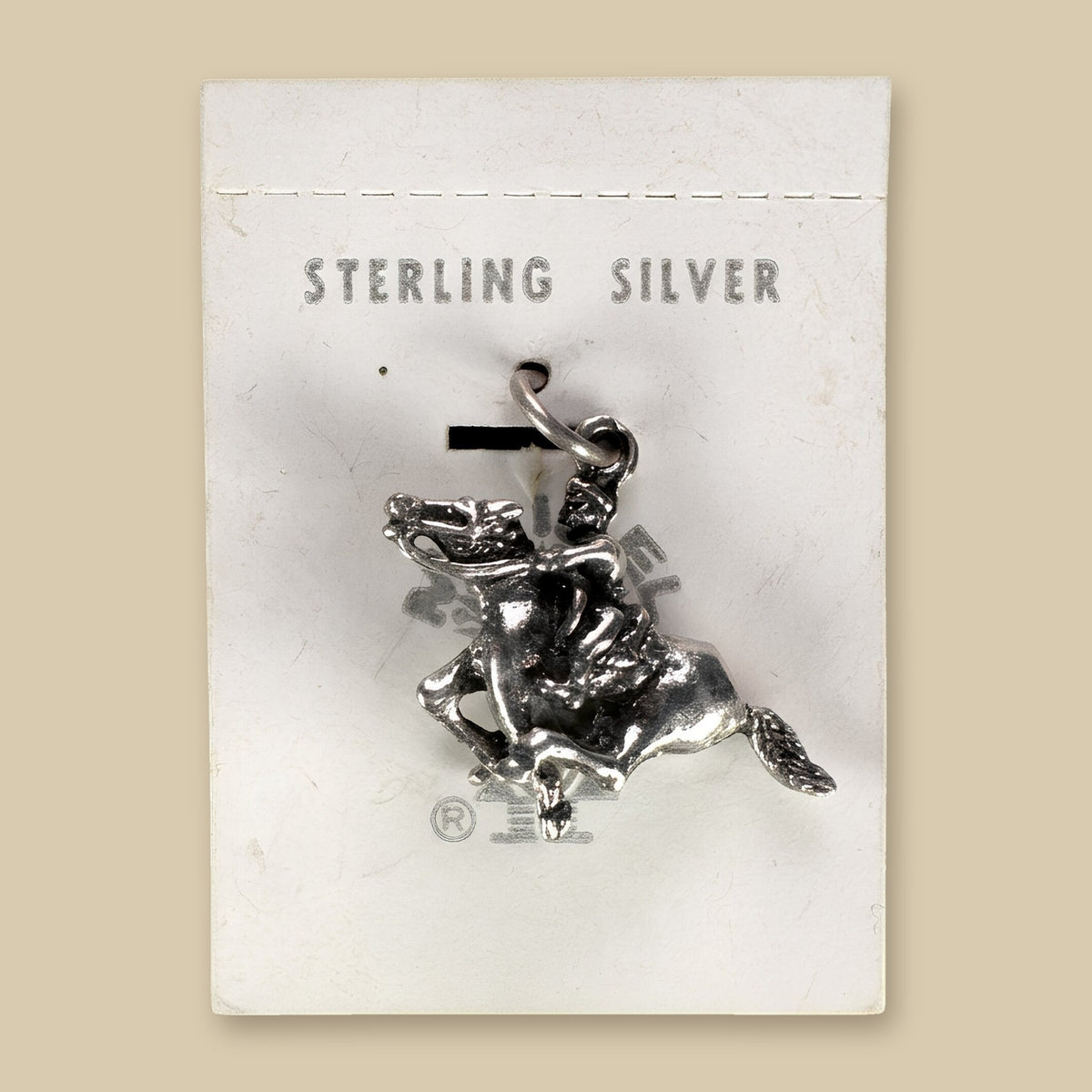Vintage Maisel's Sterling Silver Bucking Bronco Charm, New Old Stock, shown on a sand background