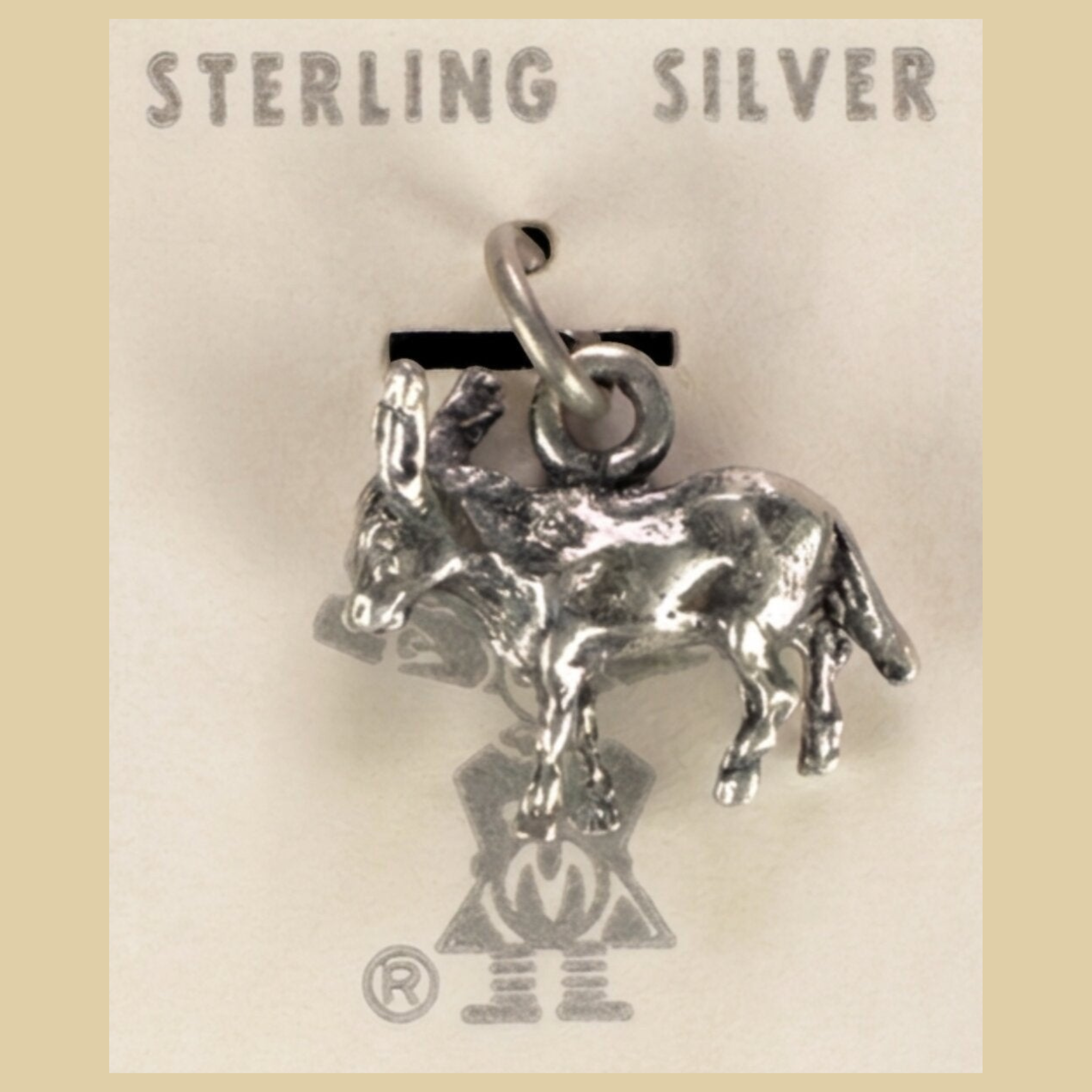 Vintage Maisel's Sterling Silver Burro Charm, New Old Stock, shown on a desert plaster background