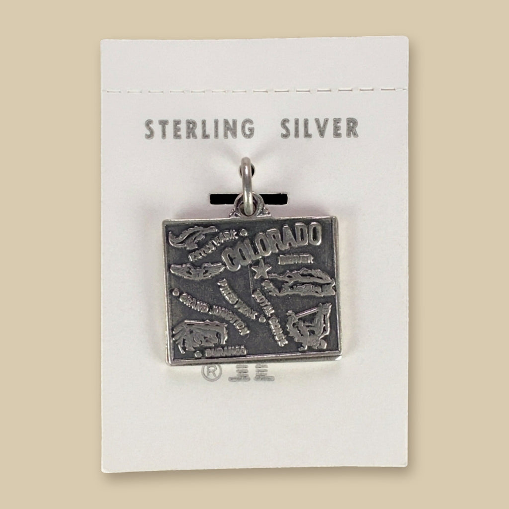 Vintage Maisel's Sterling Silver Colorado Map Charm, New Old Stock, shown on a sand background