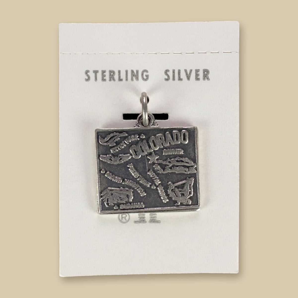 Vintage Maisel's Sterling Silver Colorado Map Charm, New Old Stock, shown on a sand background