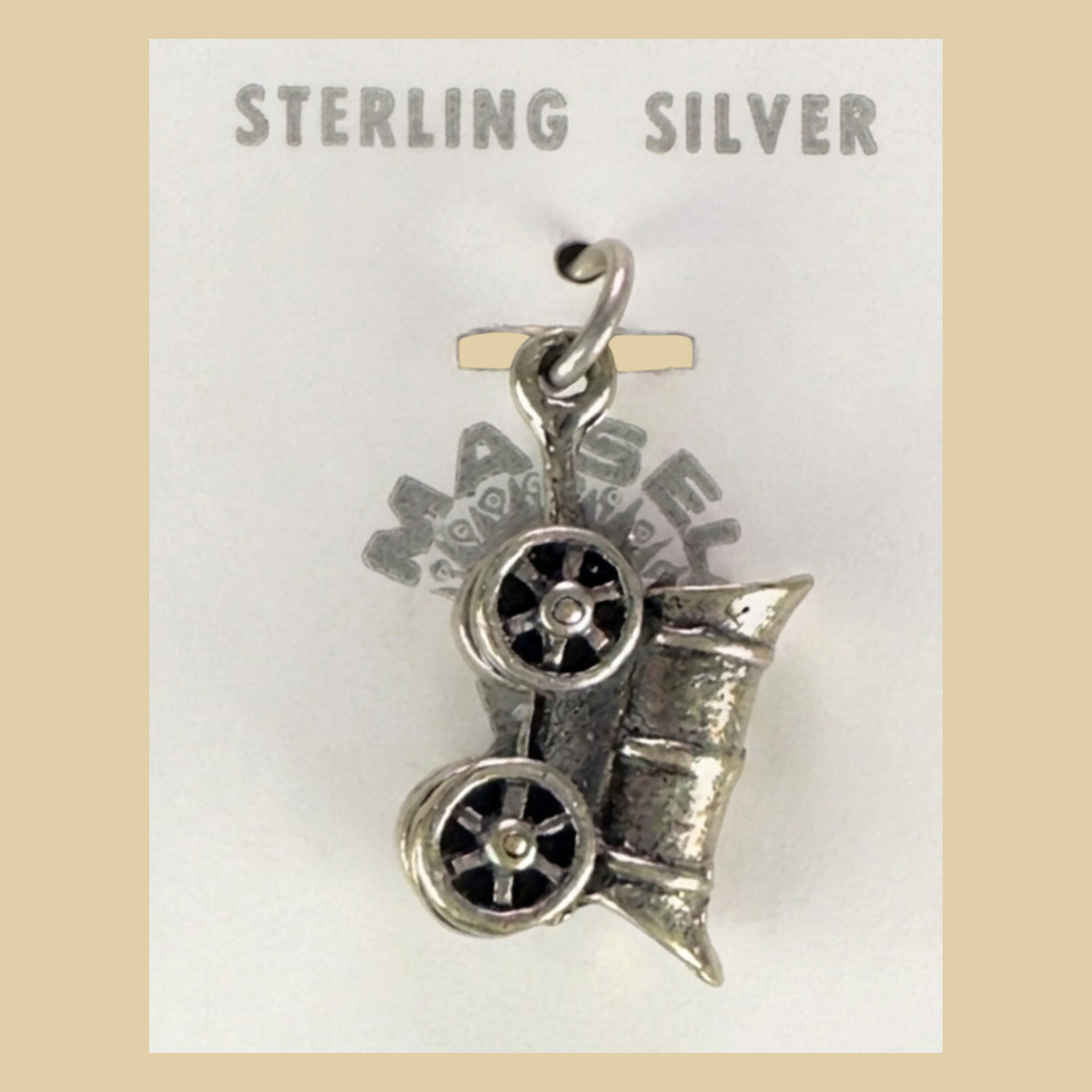 Vintage Maisel's Sterling Silver Covered Wagon Charm, New Old Stock, shown on a desert plaster background