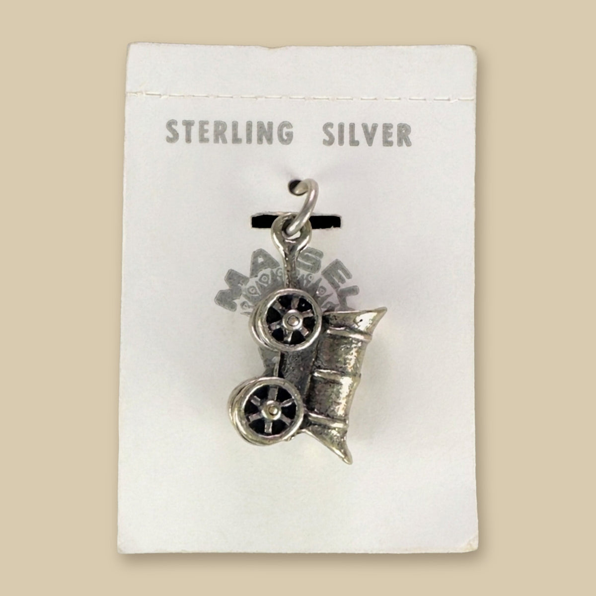 Vintage Maisel's Sterling Silver Covered Wagon Charm, New Old Stock, shown on a sand background