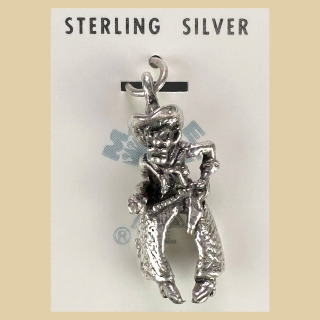 Vintage Maisel's Sterling Silver Cowboy Charm, New Old Stock, shown on a desert plaster background