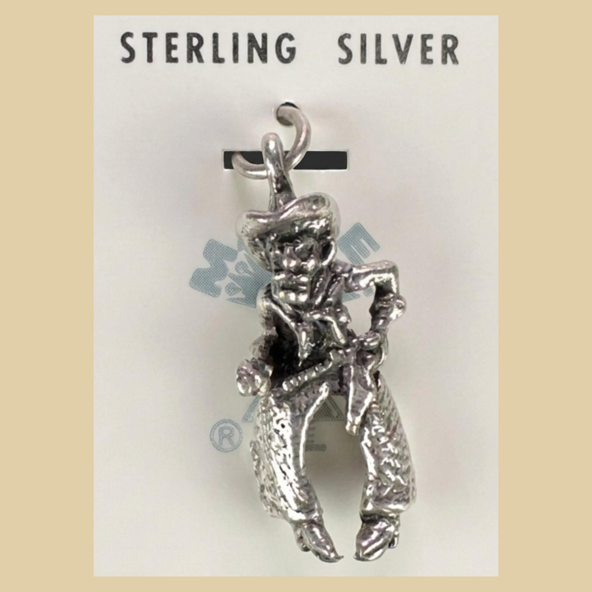Vintage Maisel's Sterling Silver Cowboy Charm, New Old Stock, shown on a desert plaster background