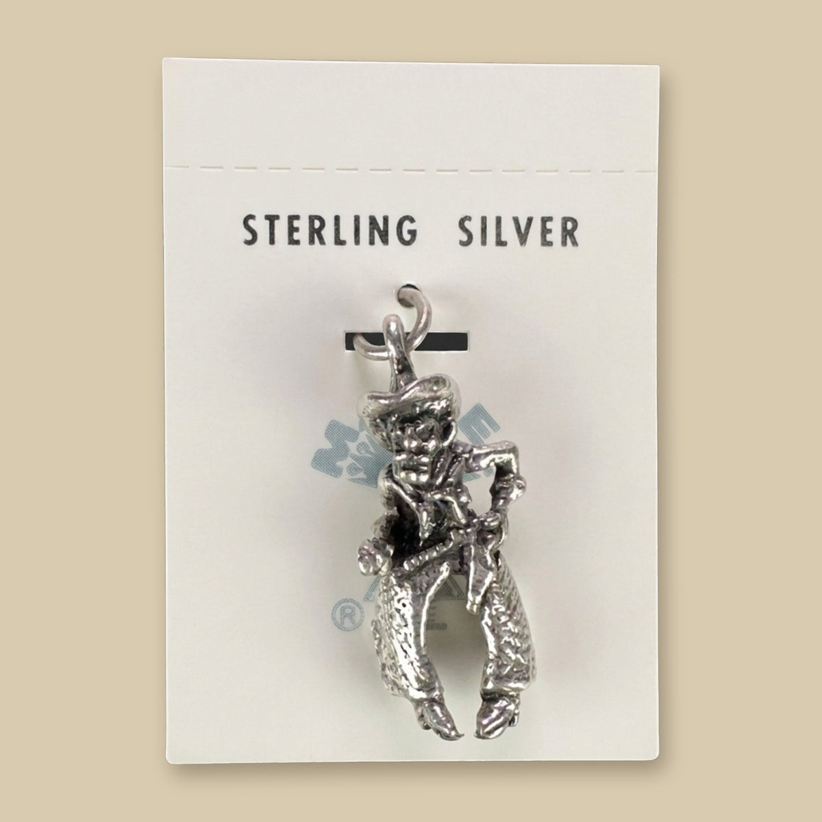 Vintage Maisel's Sterling Silver Cowboy Charm, New Old Stock, shown on a sand background