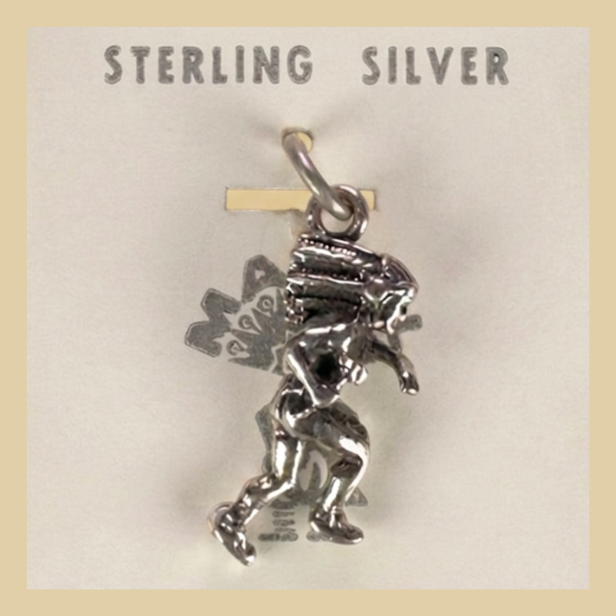 Vintage Maisel's Sterling Silver Dancer in Headdress Charm, New Old Stock, shown on a desert plaster background