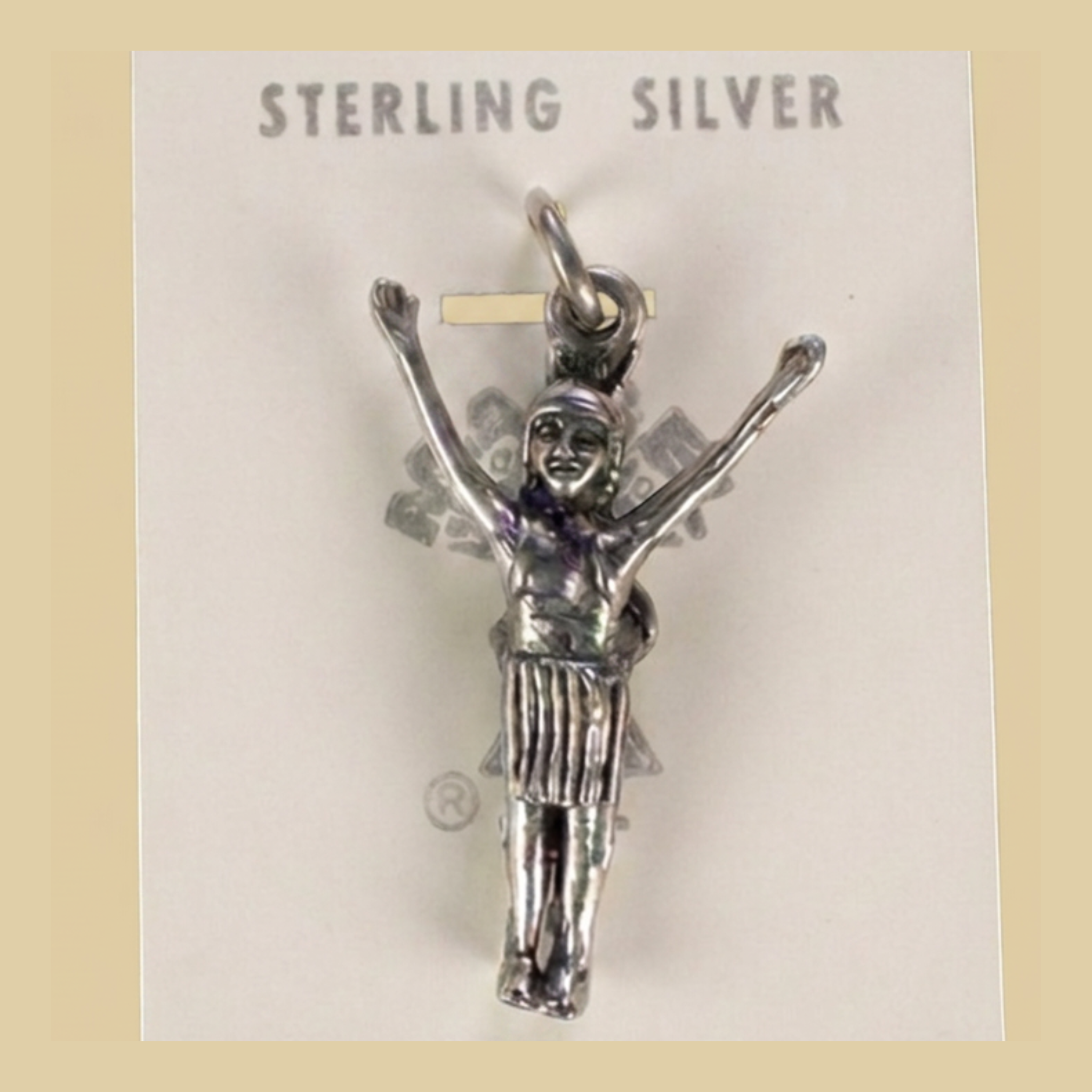 Vintage Maisel's Sterling Silver Figure with Arms Raised Charm, New Old Stock, shown on a desert plaster background