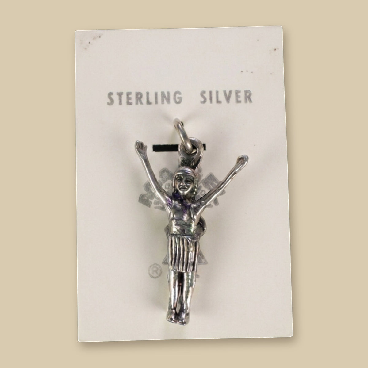 Vintage Maisel's Sterling Silver Figure with Arms Raised Charm, New Old Stock, shown on a sand background