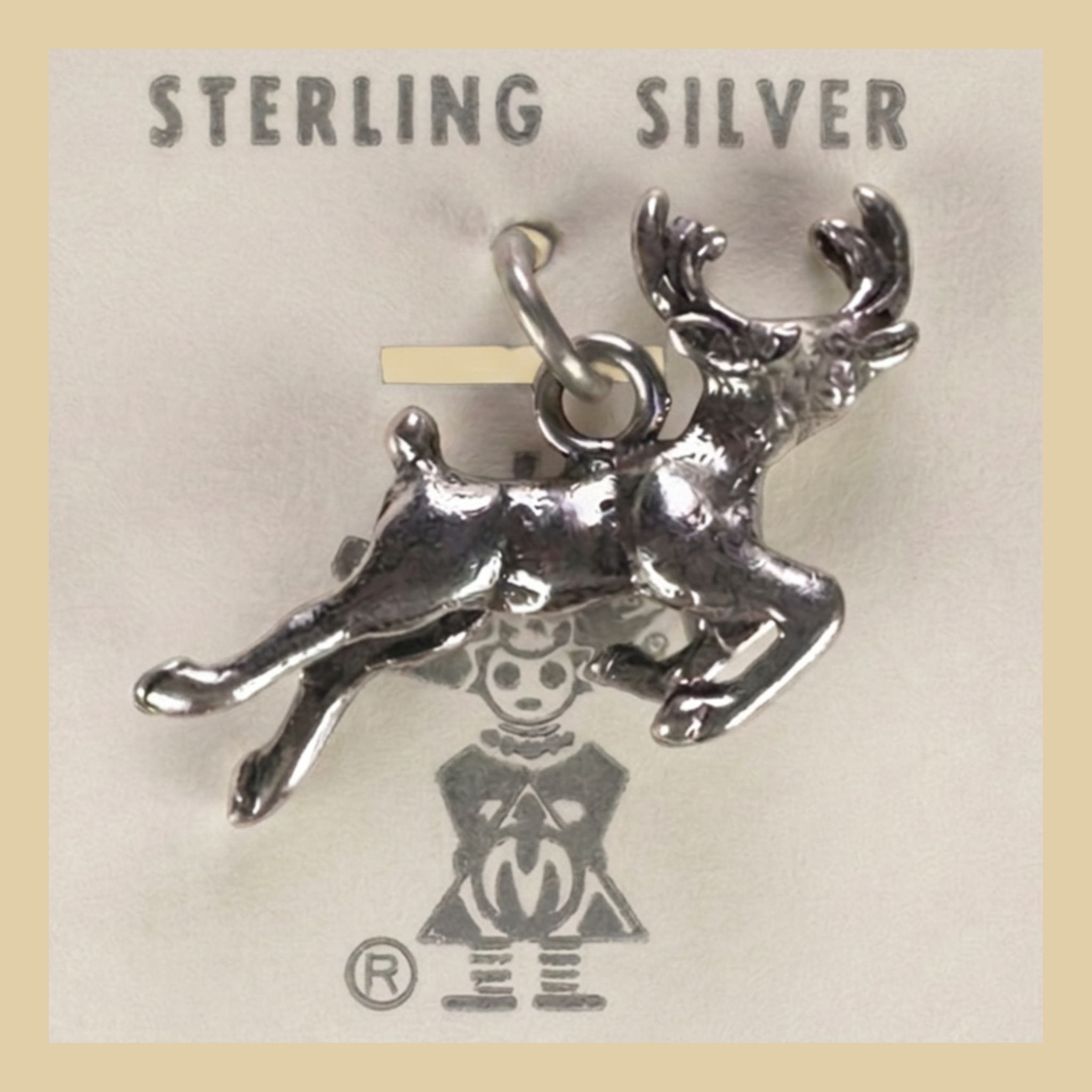 Vintage Maisel's Sterling Silver Leaping Elk Charm, New Old Stock, shown on a desert plaster background