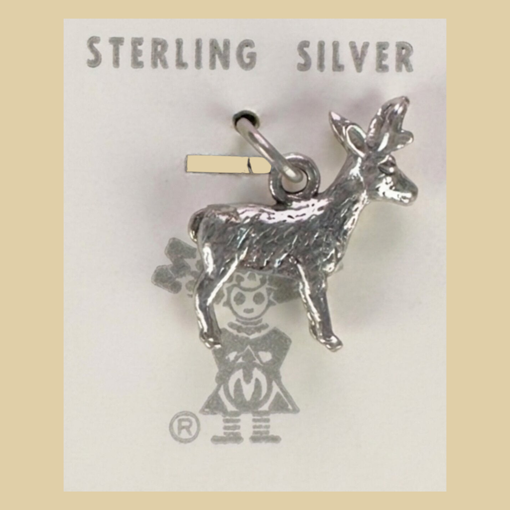 Vintage Maisel's Sterling Silver Standing Elk Charm, New Old Stock, shown on a desert plaster background