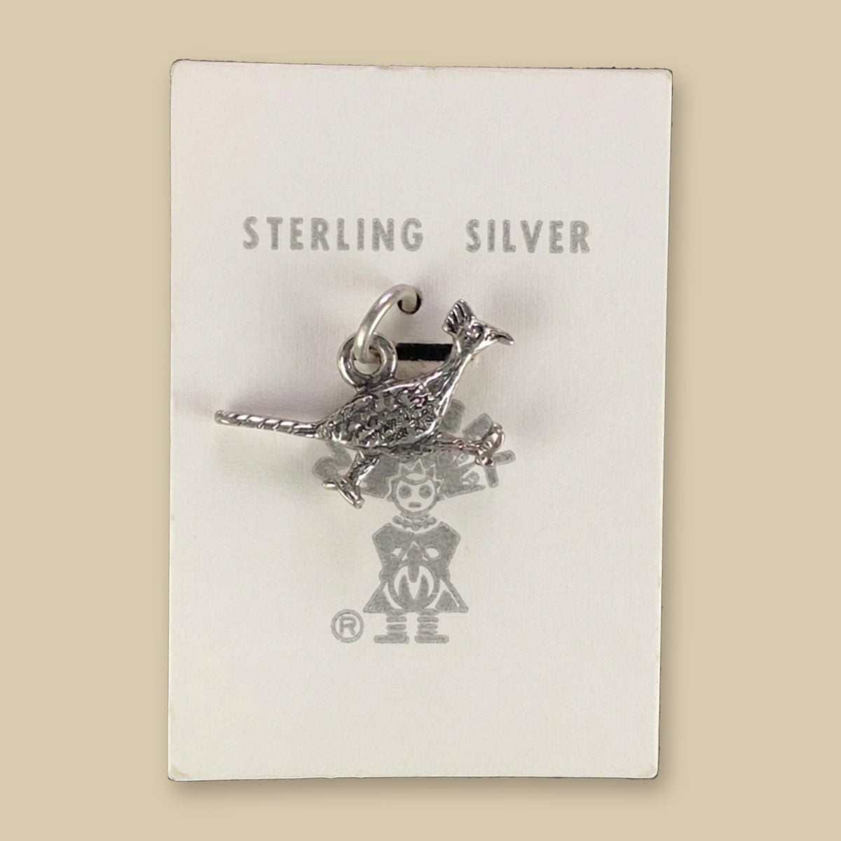 Vintage Maisel's Sterling Silver Textured Roadrunner Charm, New Old Stock, shown on a sand background