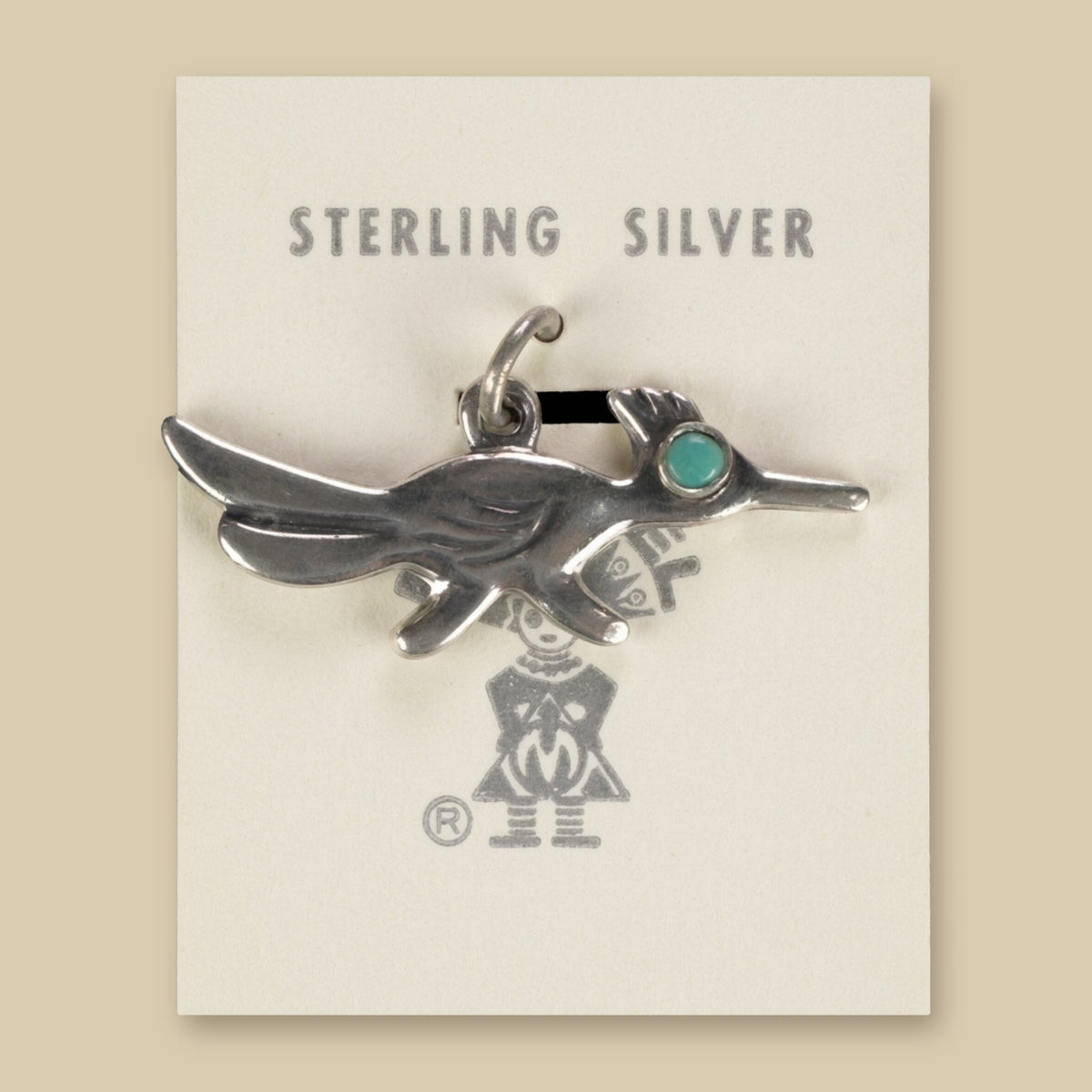 Vintage Maisel's Sterling Silver Turquoise Eye Roadrunner Charm, New Old Stock, shown on a sand background