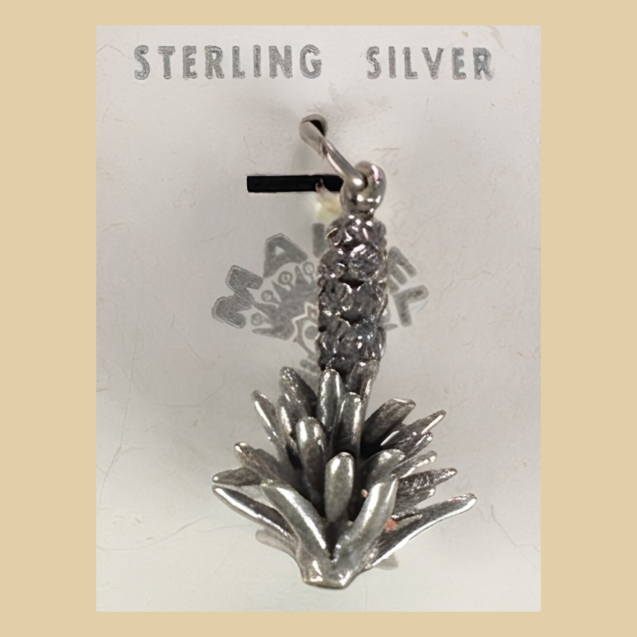 Vintage Maisel's Sterling Silver Yucca Charm, New Old Stock, shown on a desert plaster background