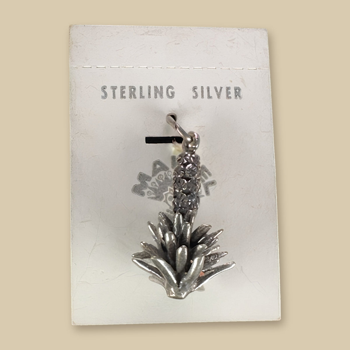 Vintage Maisel's Sterling Silver Yucca Charm, New Old Stock, shown on a sand background