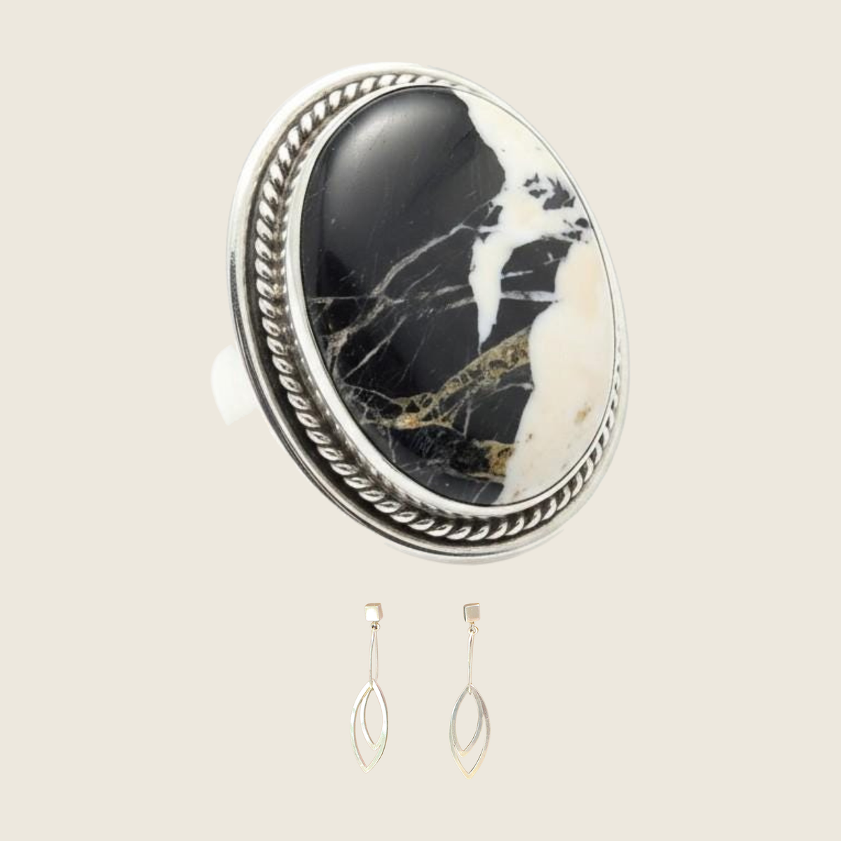 White buffalo ring and leaf dangle earrings jewelry set in sterling silver, shown on a bone linen background