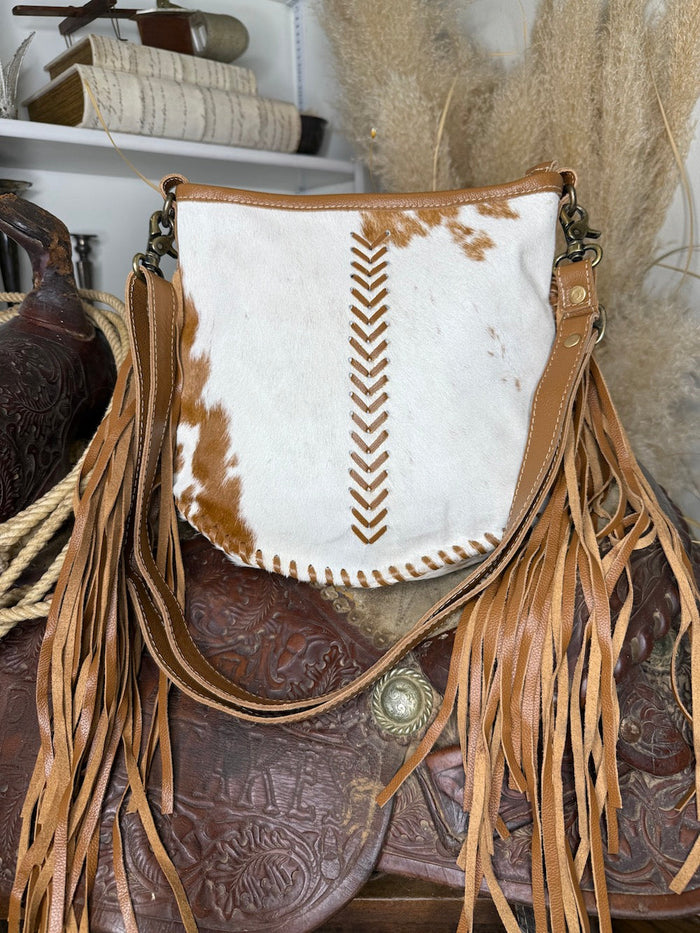 Western shoulder bag in white and brown hair-on cowhide with tan chevron lacing and long leather fringe