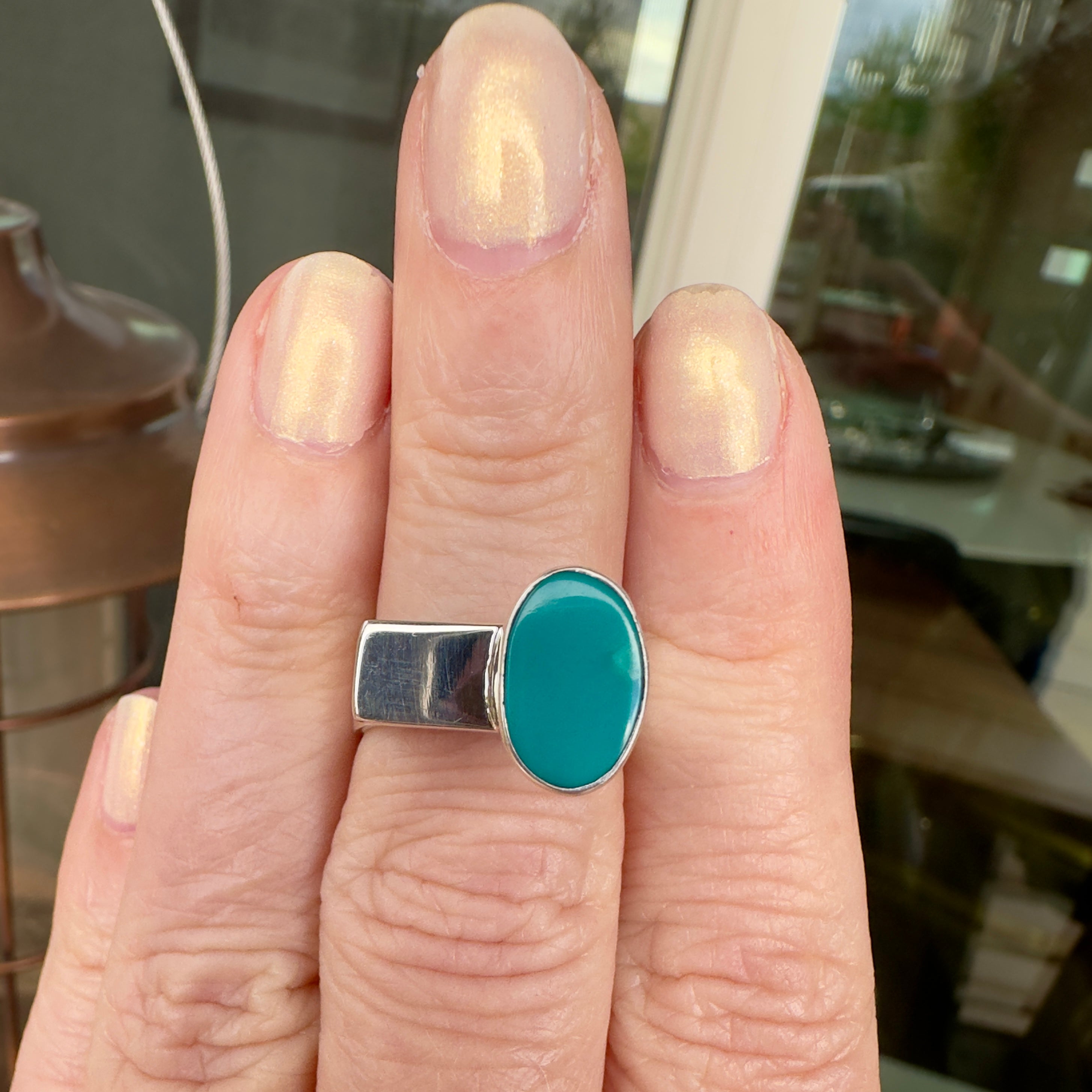 Wildflower Artisans BALAAM sterling silver ring featuring an oval teal turquoise cabochon on a wide flat band.