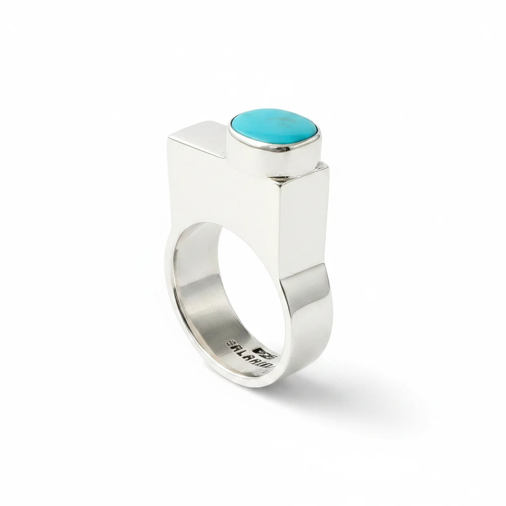 Wildflower Artisans BALAAM sterling silver ring with an off-center oval teal turquoise cabochon on a wide flat band.