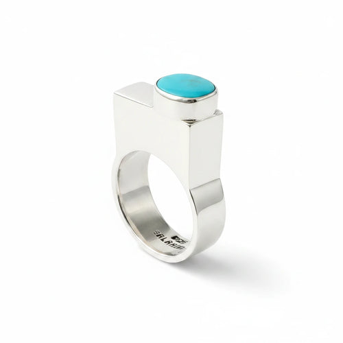 Wildflower Artisans BALAAM sterling silver ring with an off-center oval teal turquoise cabochon on a wide flat band.