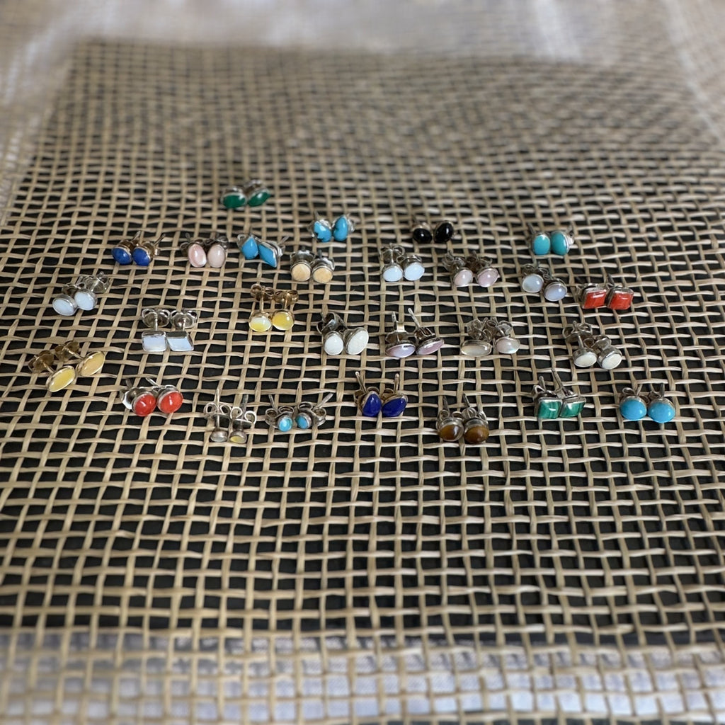 Wildflower Artisans round mother of pearl stud earrings in sterling silver settings displayed on a textured mat.