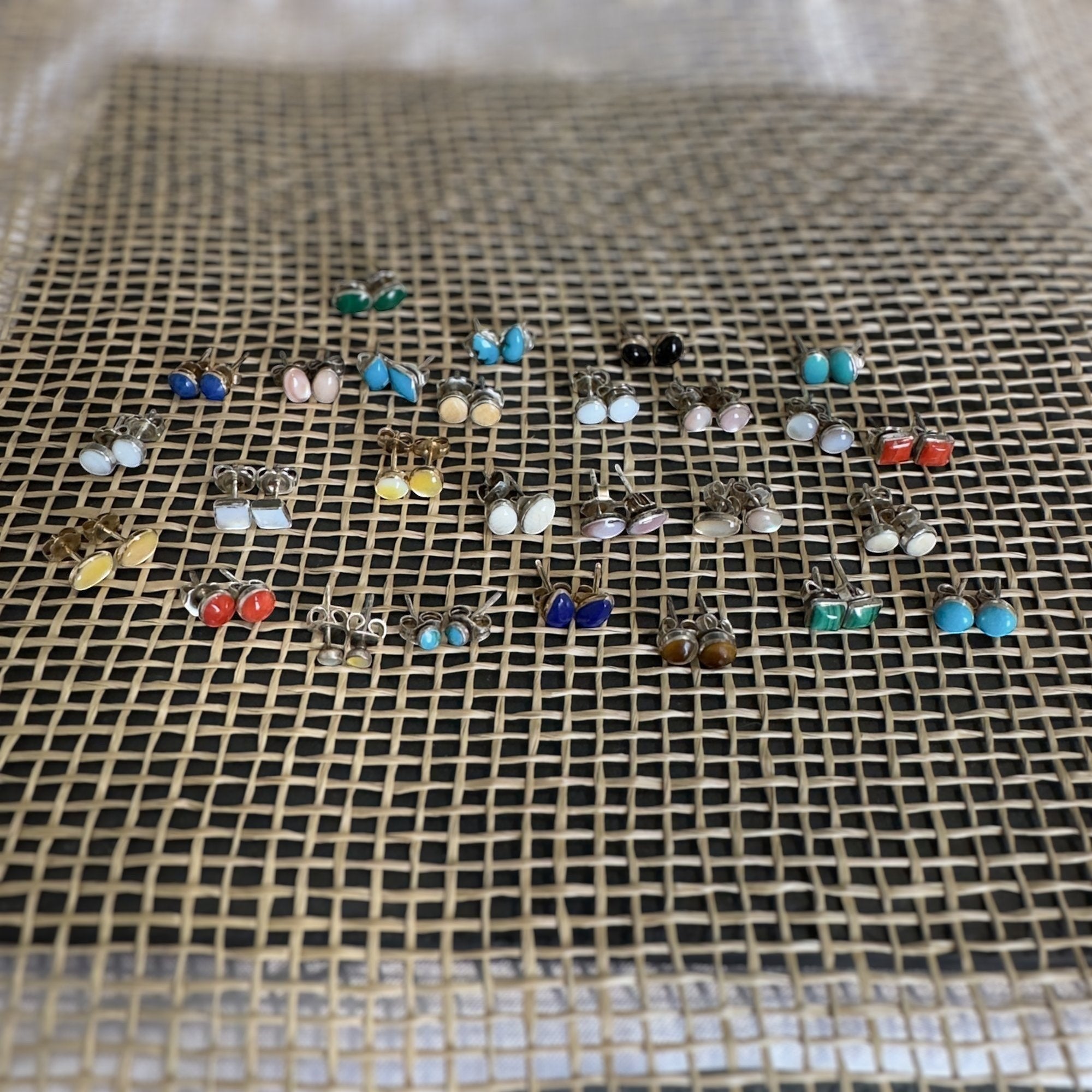 Wildflower Artisans round mother of pearl stud earrings in sterling silver settings displayed on a textured mat.
