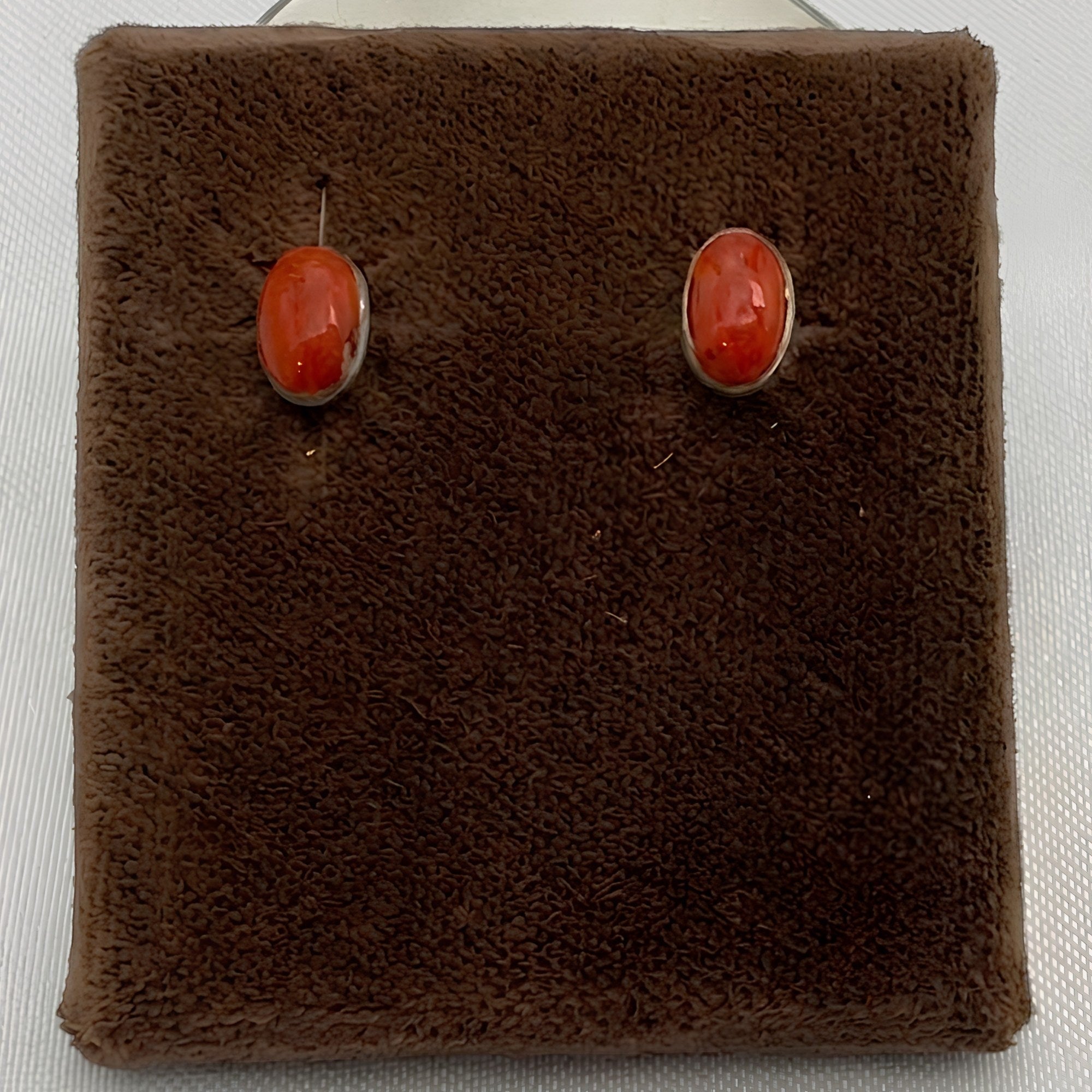Wildflower Artisans oval spiny oyster stud earrings with red-orange cabochons set in polished sterling silver bezels.