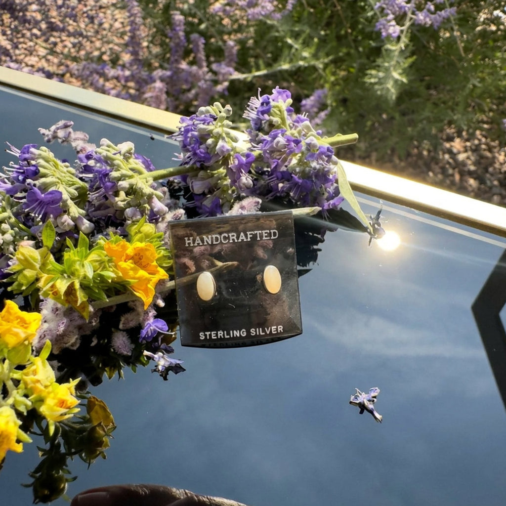 Wildflower Artisans oval stone stud earrings in sterling silver displayed on a card with purple and yellow flowers.