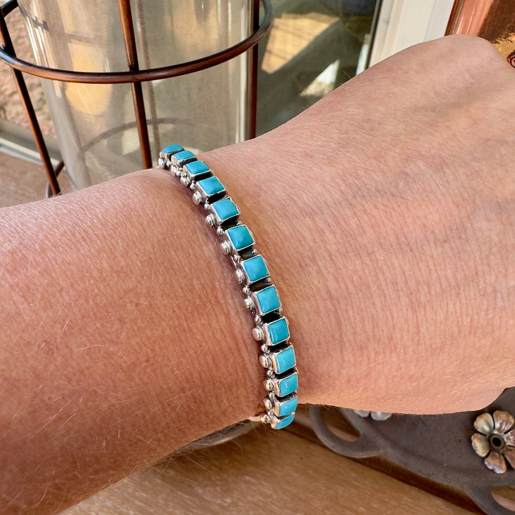 Wildflower Artisans sterling silver cuff bracelet featuring square Sleeping Beauty turquoise stones on a wrist
