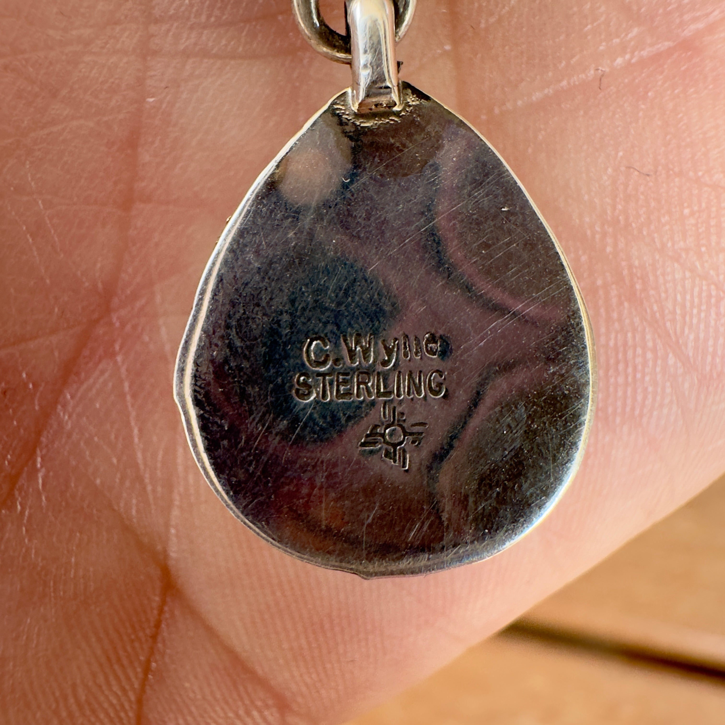 Wildflower Artisans sterling silver pendant back showing C. Wylle hallmark and Zia sun symbol stamp