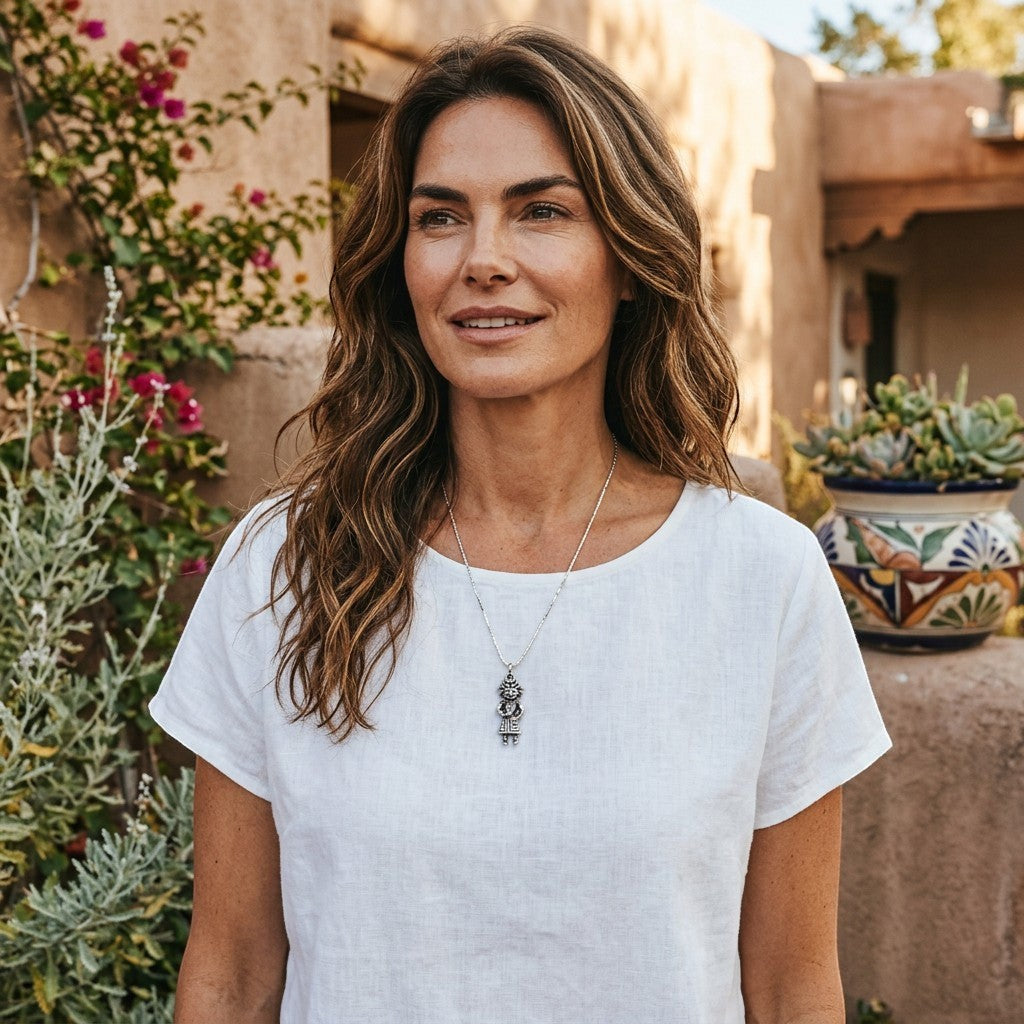 Wildflower Artisans vintage sterling silver Maisel's standing figure charm necklace worn by a woman in a white top.